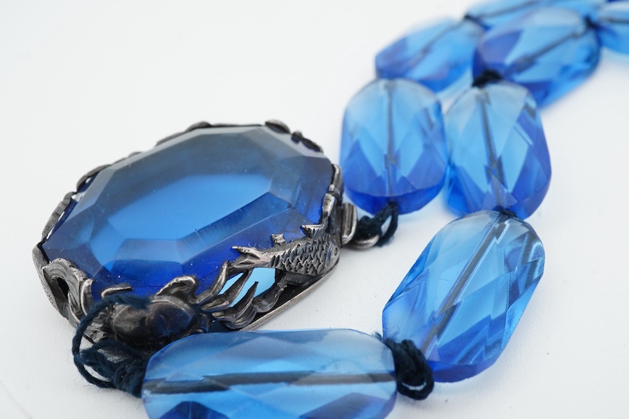 A silver and paste necklace, composed of faceted blue paste beads, the clasp set with a blue paste, in a silver mount decorated with sea creatures, length 40cm, Chinese mark for silver, maker's mark CHC